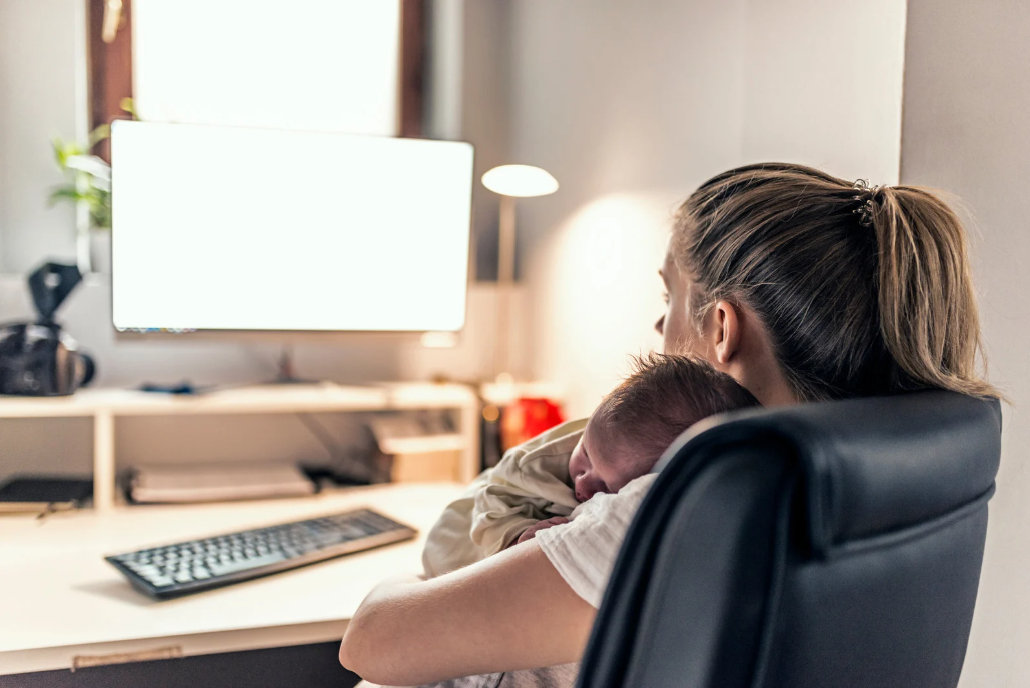 Maman travaillant à son bureau, son bébé endormi contre elle