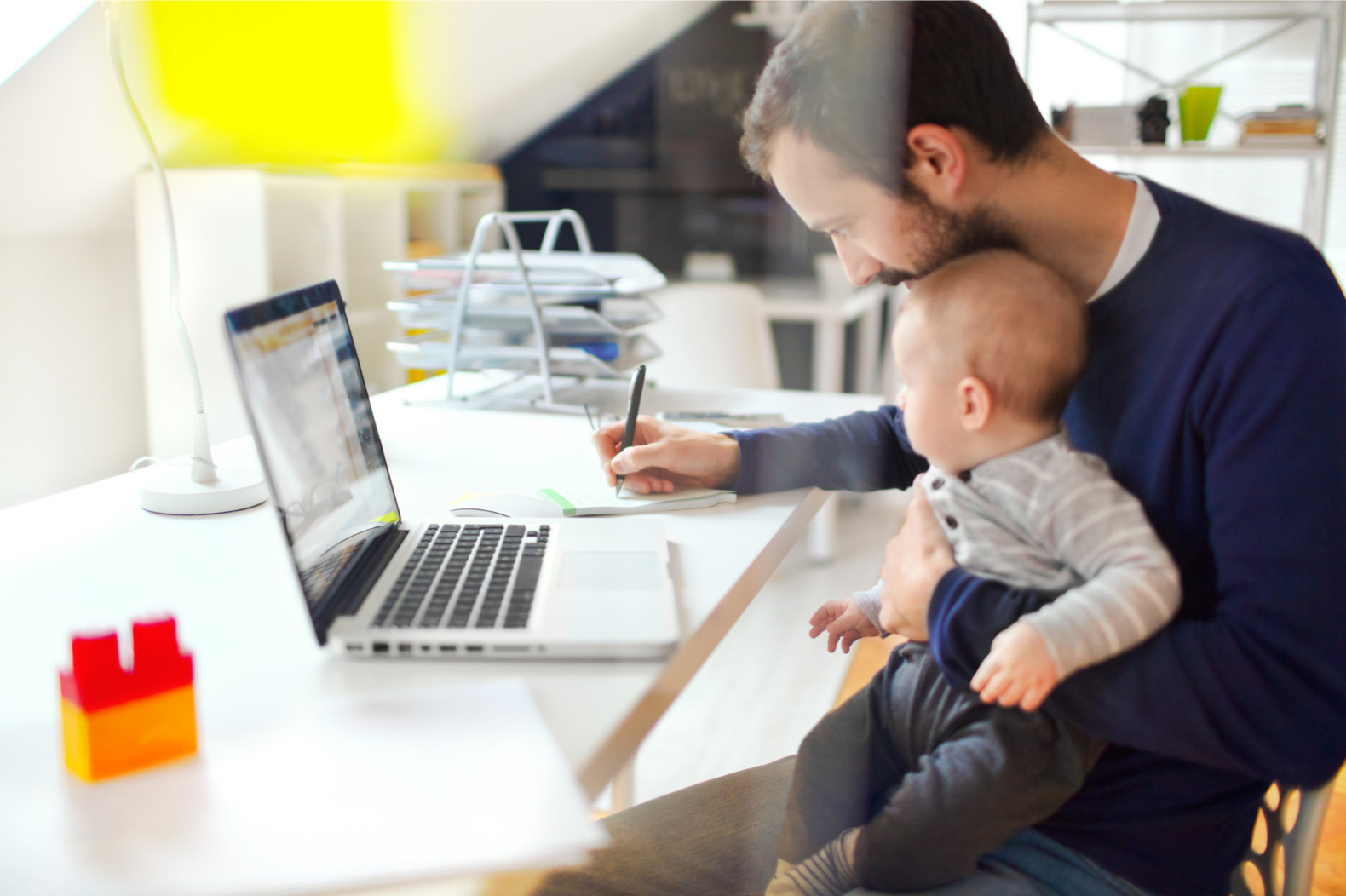 Papa travaillant à son bureau avec son bébé dans les bras